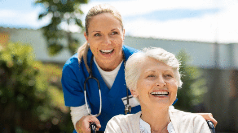 A caregiver and an older woman smiling together outdoors.