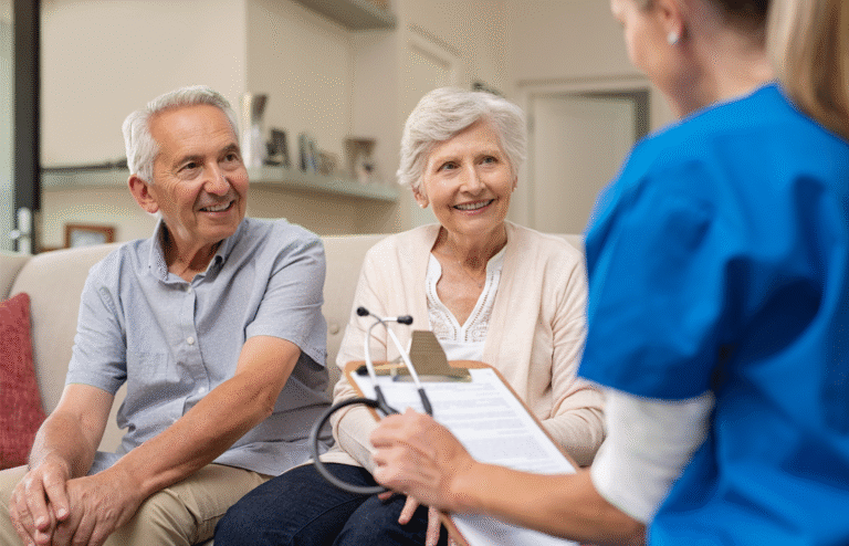 An older couple speaking with a caregiver in their living room.