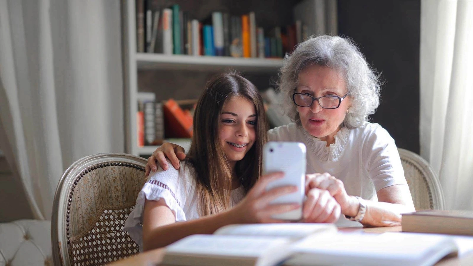 BestCareMatch | Contact BestCareMatch™ An older woman and a girl look at a smartphone together at home. BestCareMatch editorial photo.